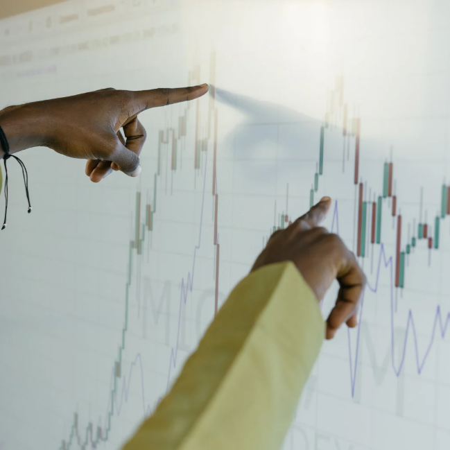 Manos señalando gráfico de velaas en pantalla táctil durante análisis del precio de un activo