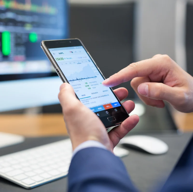 Persona operando acciones bursátiles desde el móvil con aplicación de trading